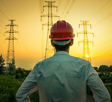 A person with building helmet standing in front of current mast